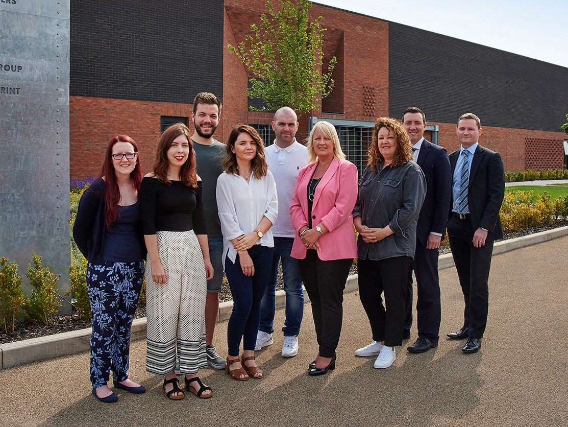A group of people stood outside a brick office building