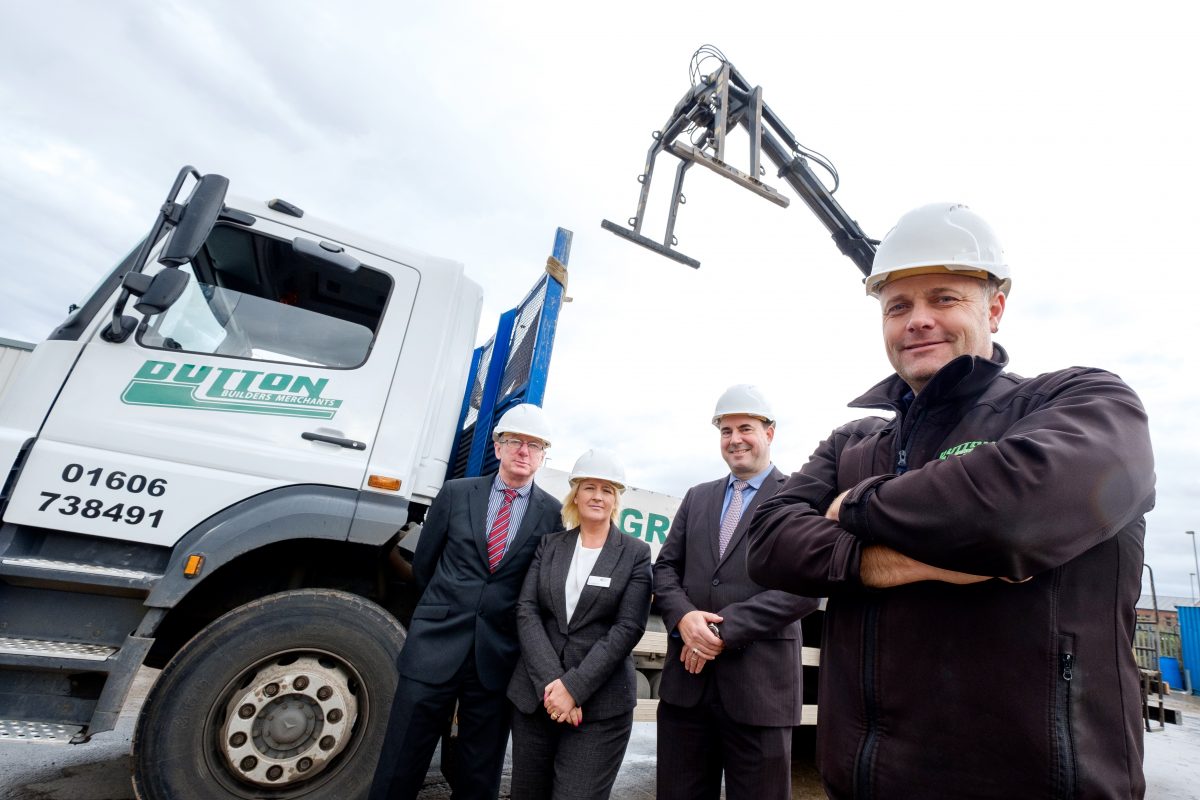 Four people wearing hard hats outside next to a truck. There is a woman in the group.
